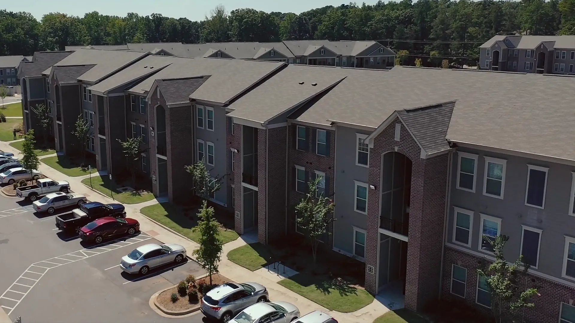 Three-story apartment buildings and their parking lot from the air