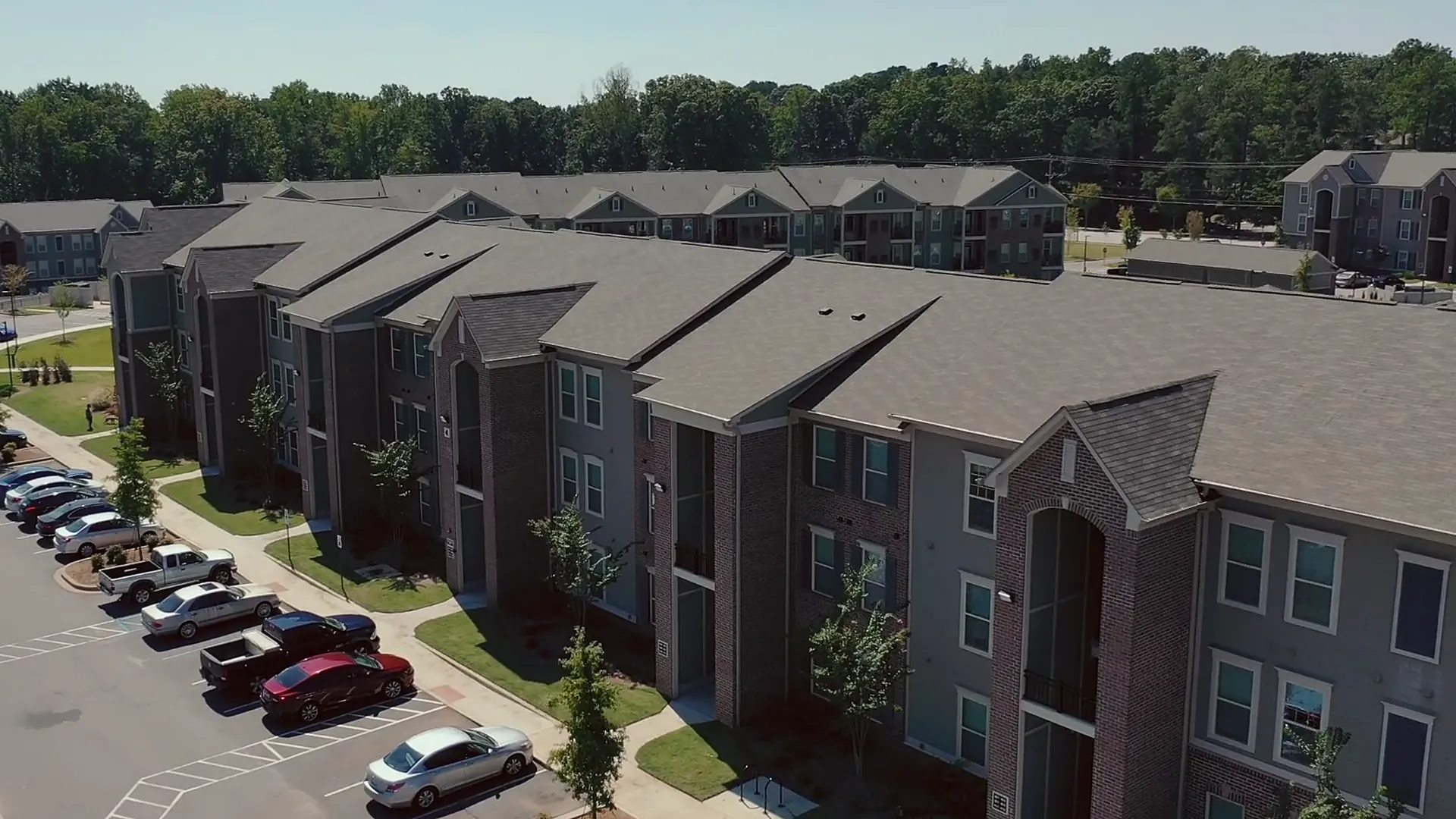 Three-story apartment buildings and their parking lot from the air