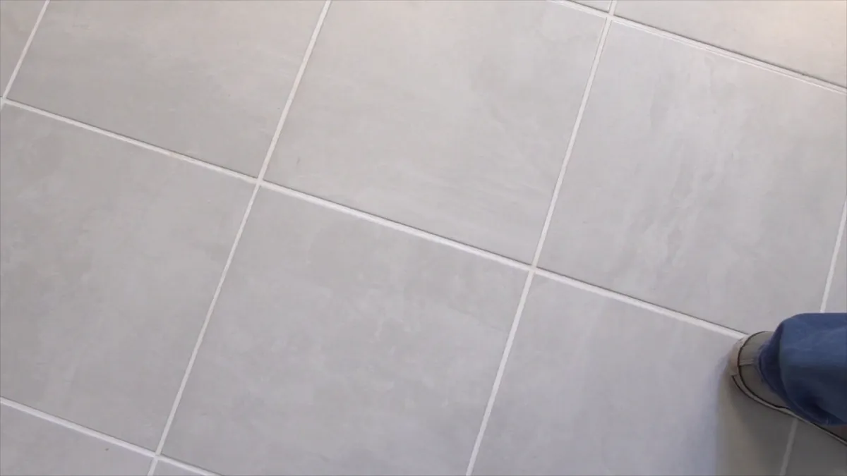 A light gray tile floor with a foot at the edge of the frame