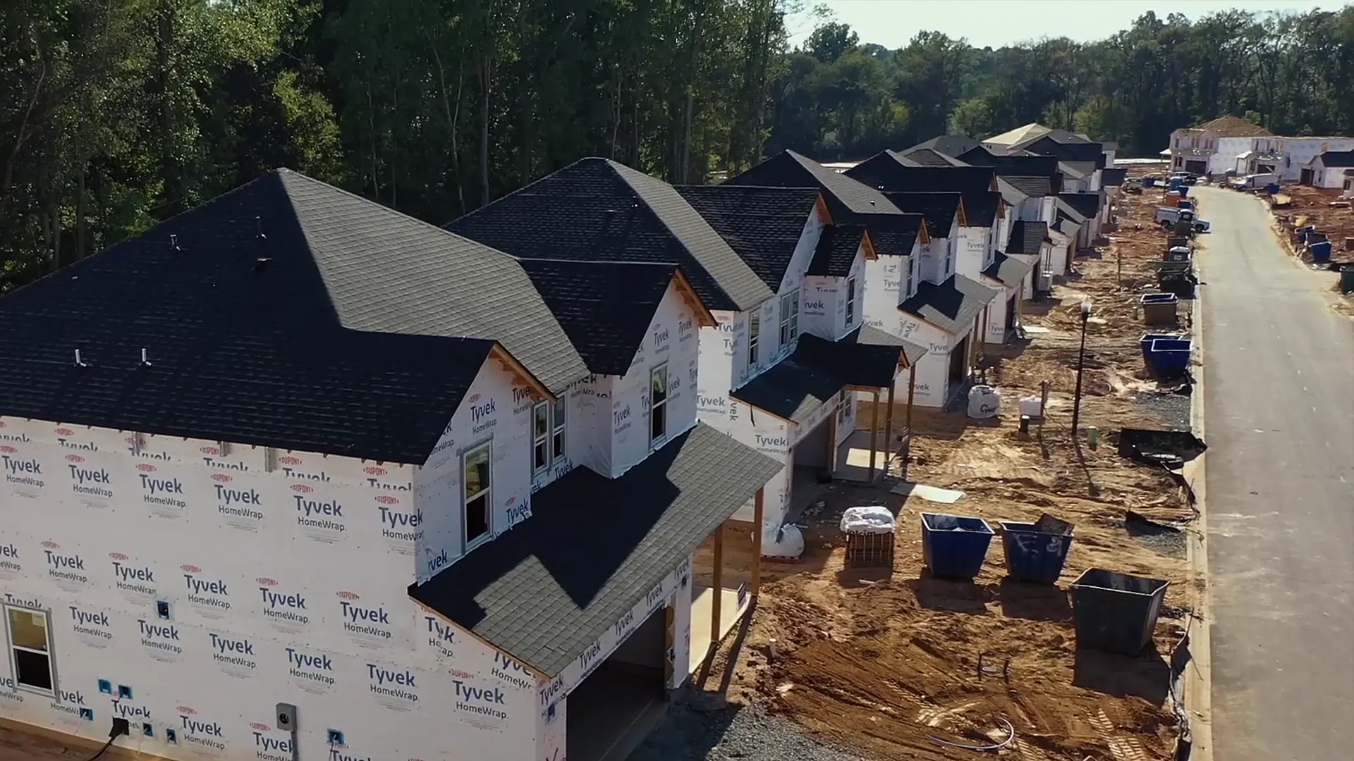 A row of new homes in house wrap beside a new street